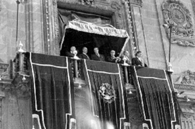 Adolfo López Mateos y Lázaro Cárdenas desde el balcón presidencial observando el desfile con motivo de la Revolución