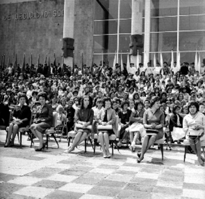 Mujeres con atuendos regionales en el escenario, acompañados en orquesta, durante la visita de Víctor Paz Estenssoro a la Unidad Independencia
