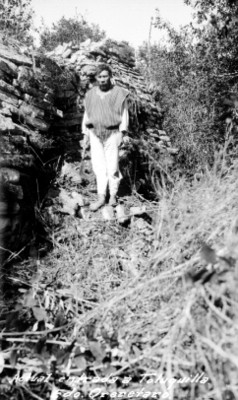 Hombre con sarape y herramienta junto a ruinas de Toluquilla