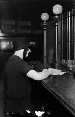 Mujer firma documentos en la ventanilla de un banco