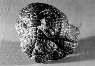 Escultura de una serpiente emplumada enroscada con lengua bífida