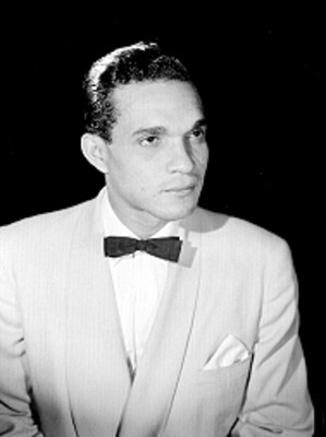 Manoco Hernandez de frente, con rostro en tres cuartos de perfil usa traje claro, retrato