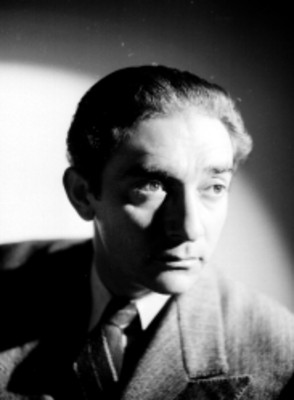 Julio Castellanos, pintor, viste de traje y corbata con el rostro de perfil, retrato