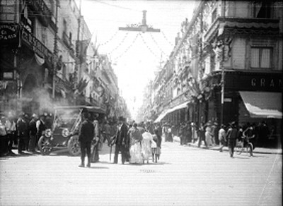 Personas caminan sobre una calle adornada a un costado de la Plaza de la Constitución