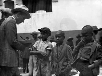Hombre realiza anotaciones frente a niños pobres