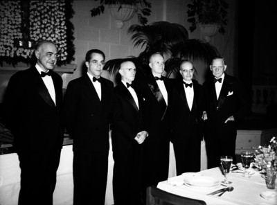 Carlos Contreras reunido con varios hombres en un salón durante un eventos social, retrato de grupo