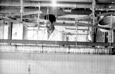 Artesanos tejen en un telar manual