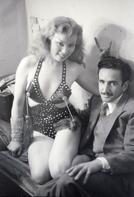 Vedette sentada en una cama junto a hombre, retrato