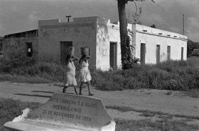 Mujeres mayas con cubeta sobre cabeza en una calle