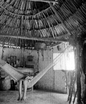 Mujer maya recostada en hamaca en el interior de su vivienda