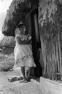 Mujer maya afuera de una casa de bajarenque