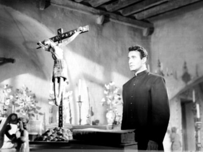 Gilbert Roland ante altar religioso, escena de película