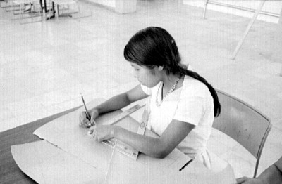 Niña lacandona realiza trazos de corte y confección