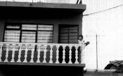 Niño sentado en el balcón de una casa