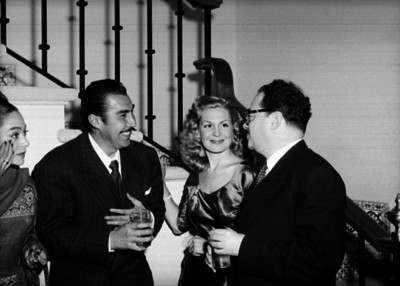 Emilio Fernández conversando con actores junto a las escaleras de una casa en una fiesta