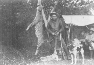 Cazadores con sus perros junto a jaguar colgado de un árbol