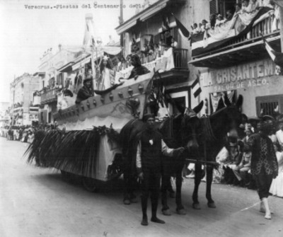 Hombres y mujer con ropajes del siglo XVI desfilan a bordo de un carro jalado por caballos