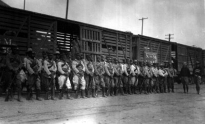 Soldados con fusiles en las manos en formación frente a un vagón de tren