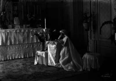 Niña hincada frente a un altar durante su primera comunión