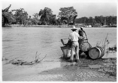 Hombres transportan tambos por el río