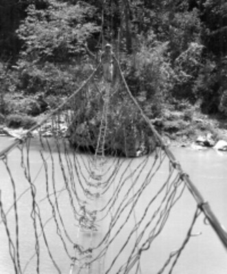 Hombre y mujer cruza un puente de alambre sobre el río Santo Domingo