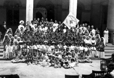Niños desvalidos rodeados de profesores y alumnos de la cruz roja, retrato