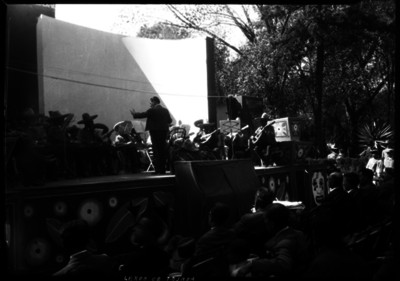 Miguel Lerdo de Tejada dirige la Orquesta Típica Mexicana en un jardín, durante un Festival Cultural