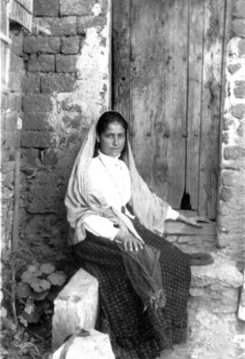 Mujer jovén sentada a la entrada de una casa rustica, retrato