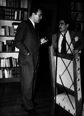 Vicente Lombardo Toledano conversa con un hombre en una biblioteca
