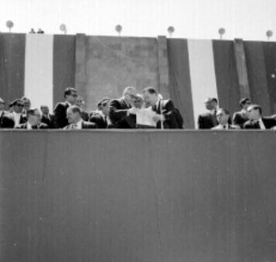 Rómulo Betancourt y Benito Coquet observando unos documentos en un presídium duranmte una ceremonia