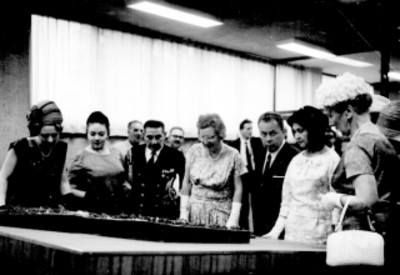 Eva Sámano, conversando con Benito Coquet y Juliana, reina, observando maqueta, en una oficina