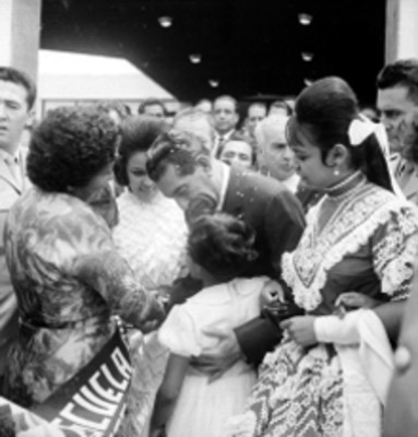 Adolfo López Mateos del brazo de mujeres caminando durante la inauguración de instalaciones del IMSS, en Chalco