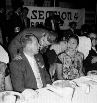 Luis Gómez Zepeda conversnado acompañado de tehuanas durante un banquete
