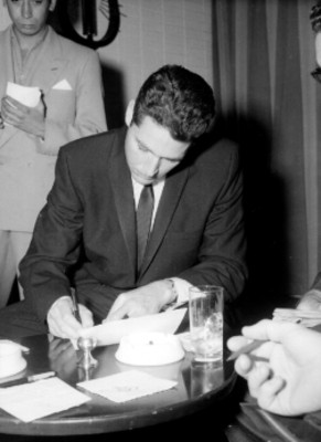 Kerwin Mathews firmando documentos en una oficina