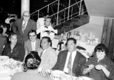 Empleados y miembros de la General Electric a la mesa, durante una posada en una casa