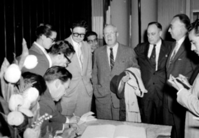 Dwight D. Eisenhower ante reporteros y funcionarios en un salón durante su llegada