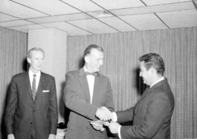 Empleado de la General Electric recibiendo un diploma durante una fiesta en casa del Sr. Calderón