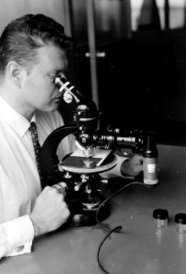 Químico observando a través de un microscopio, durante un proceso industrial en FERRO ENAMEL