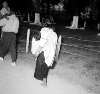 Mujer tzotzil con su hijo, caminando junto a un parque