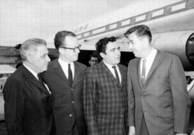 Harol Rossen, inventor del Satélite Pájaro Madrugador conversando con hombres en el aeropuerto