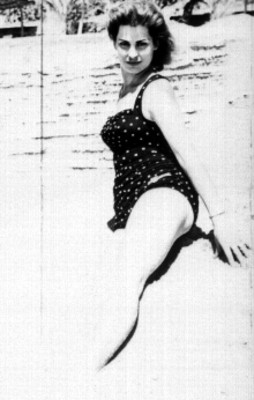 Actriz posando en traje de baño sentada en un montón de arena en la playa, retrato
