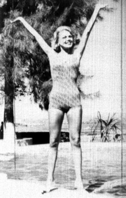 Modelo en traje de baño posando levantando los brazos junto a una piscina, retrato