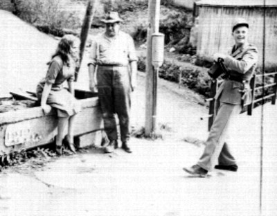 Actores conversando frente a unas casas rústicas, escena de película