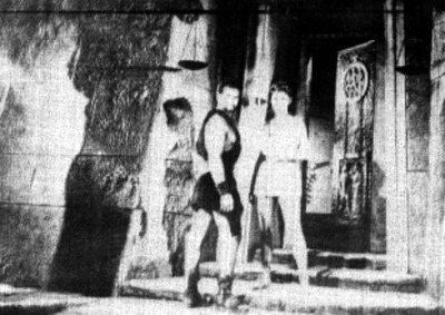 Pareja de actores vestidos de romanos frente a un templo, escena de película