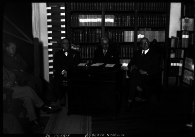 Roberto Medellin Ostos, rector de la UNAM conversando con catedráticos en una biblioteca