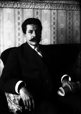 Hilario Medina, vestido de traje, sentado en un sillón, retrato