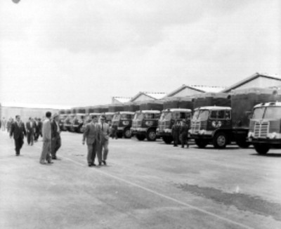 Roberto Amorós, Mariano López Mateos y demás personalidades caminan frente a unos trailmóviles de C.E.I.M.S.A.
