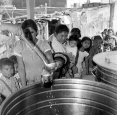 Cocinero repartiendo comida a mujeres y niños en un barrio pobre
