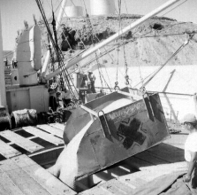 Trabajador vaceando trigo con una tolva en la bodega del barco Constitución