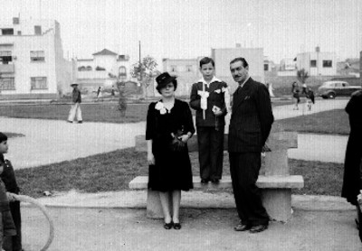 Niño posando con una pareja en un parque durante su primera comunión, retrato de familia